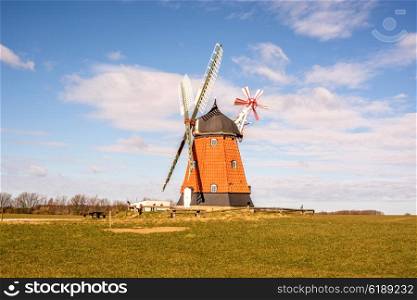 Old mill on a green meadow with blue sky