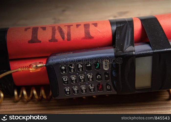 old mobile phone connected by a twisted cable with a detonator of three TNT blocks. dynamite with phone