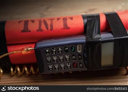 old mobile phone connected by a twisted cable with a detonator of three TNT blocks. dynamite with phone