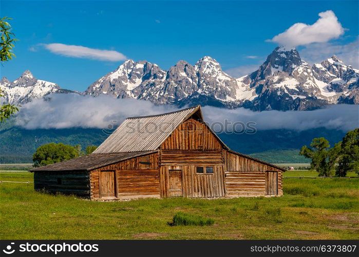 Old mormon barn in Grand Teton Mountains with low clouds. Grand Teton National Park, Wyoming, USA.