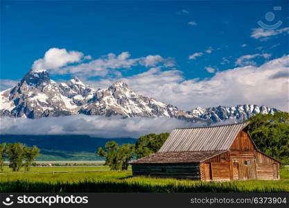 Old mormon barn in Grand Teton Mountains with low clouds. Grand Teton National Park, Wyoming, USA.