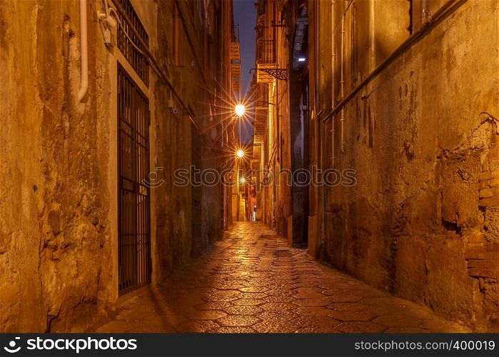Old narrow medieval street in the light of lanterns. Palermo. Sicily. Italy.. Palermo. Old medieval street in night lighting.