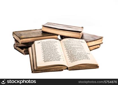 Old neglected books placed in to a small heap of two stacks with one of the books open and leaning against the stacks facing the viewer, all on a white background.