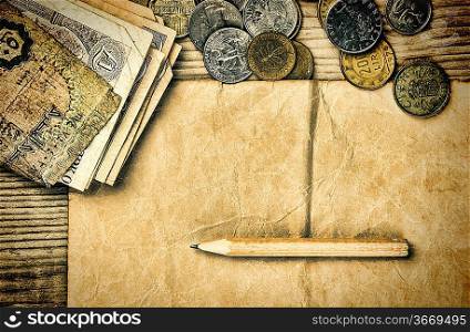 Old notes and coins and pencil on a wooden table