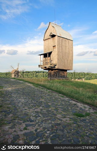 Old obsolete windmill building and stone pave road