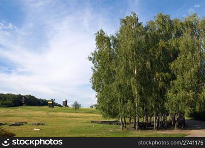 Old obsolete windmills beyond the trees plantation on field