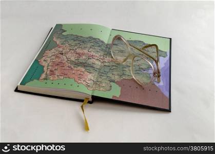 Old open notebook with map of Bulgaria and spectacles