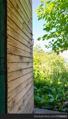Old open wooden door against garden