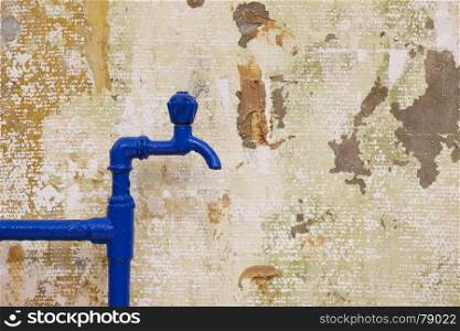 Old painted blue tap and pipes on textured grunge wall background, copy space
