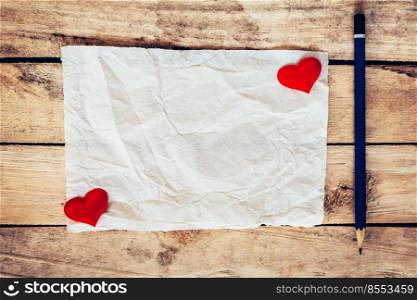 old paper and red heart with pencil on wood background for valentine greeting card.