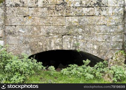 Old partially buried stone arch, under bed of disused canal. Creech St Michael, Somerset, England, United Kingdom.