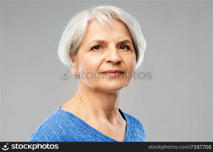 old people concept - portrait of senior woman in blue sweater over grey background. portrait of senior woman in blue sweater over grey