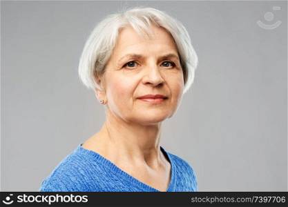 old people concept - portrait of senior woman in blue sweater over grey background. portrait of senior woman in blue sweater over grey