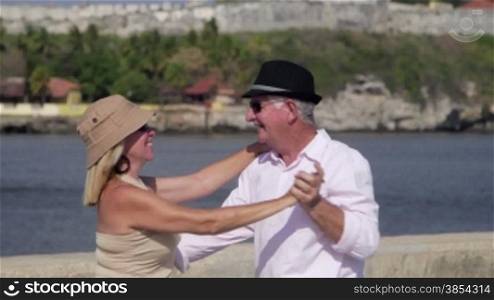 Old people traveling, husband and wife having fun, dancing and kissing on vacation near the sea