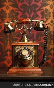 old phone is made of metal on a wooden table. withdrawn against the arnament. focus on phone
