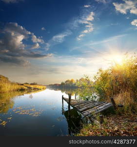 Old pier on autumn river at sunset