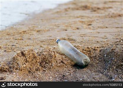 Old plastic bottles on the sand beach at sea.