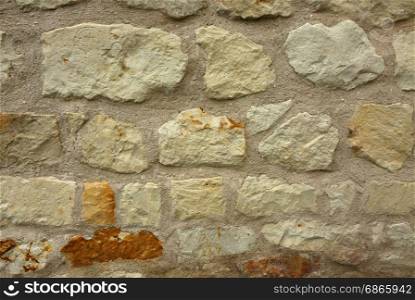 Old, porous stone wall as a very interesting background and texture. Horizontal view.