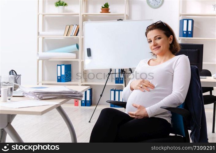 Old pregnant woman working in the office 