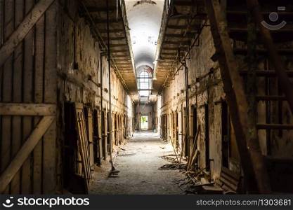 Old prison dark hallway with grunge wooden staircases and doors.