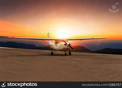 old propeller plane taxi on airport runway against beautiful sun set sky