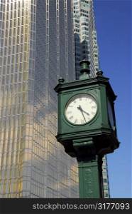 Old public clock with tall modern skyscraper in the background