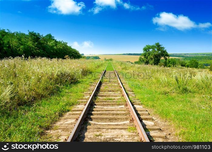 Old railway track among summer fields.