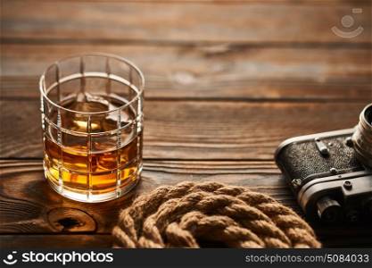 Old rangefinder camera and whiskey. Glass of whiskey and vintage old 35mm rangefinder camera on wooden background