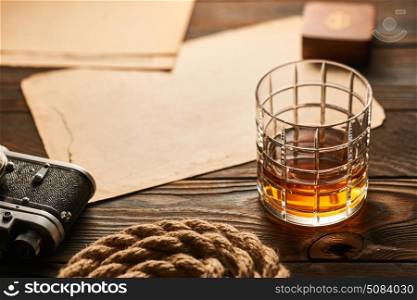 Old rangefinder camera and whiskey with antique map. Glass of whiskey and vintage old 35mm rangefinder camera on wooden background with antique XIX century map