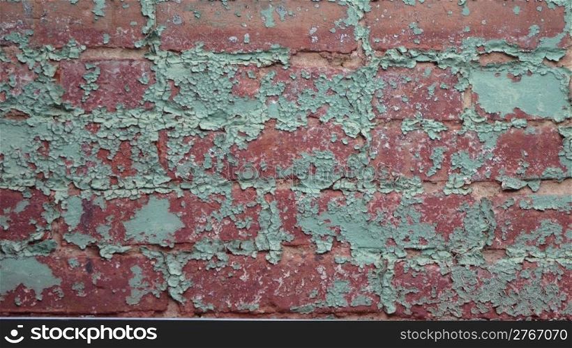 Old red brick wall with green chipped paint