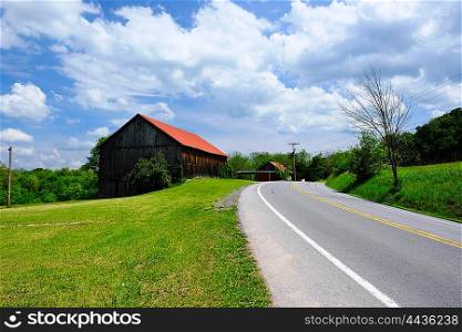 Old red roof barn near highway in Pennsylvania at sunny summer day