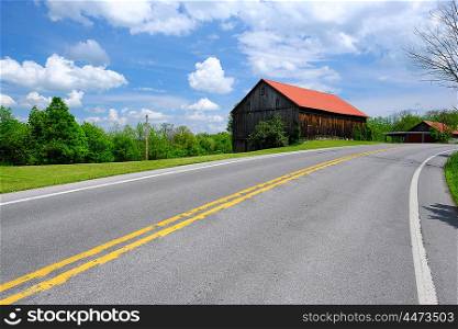 Old red roof barn near highway in Pennsylvania at sunny summer day