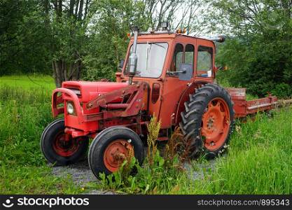 Old red tractor near forest in Norway