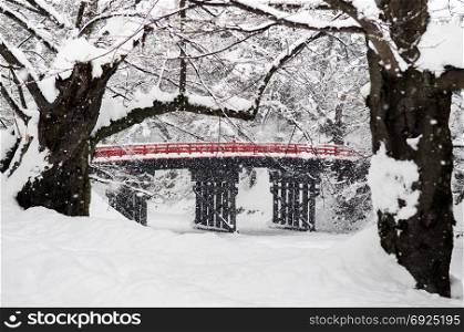 Old red wooden bridge of Hirosaki Castle during snow fall in winter season, Aomori, Tohoku, Japan
