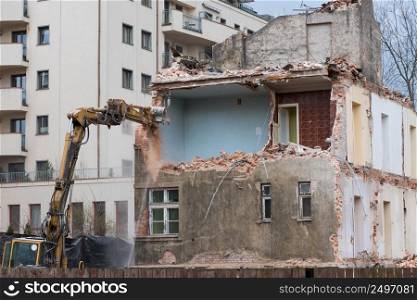 Old residential building demolition with excavator