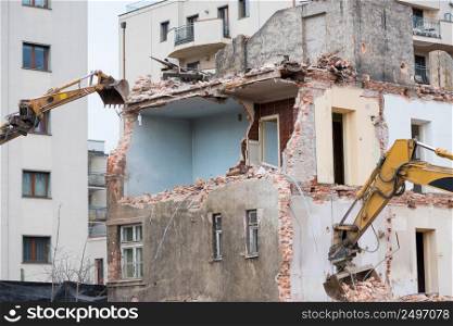 Old residential three story building demolition with hydraulic excavators