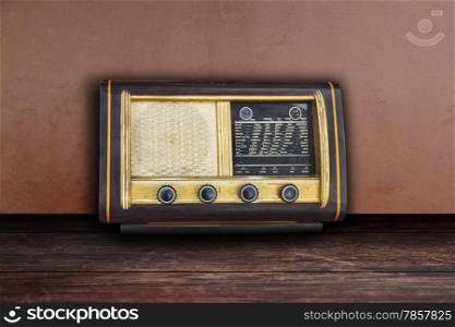 Old retro fashioned radio on wooden table and wall background