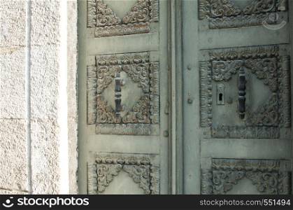 Old retro iron house front door on stone wall facade