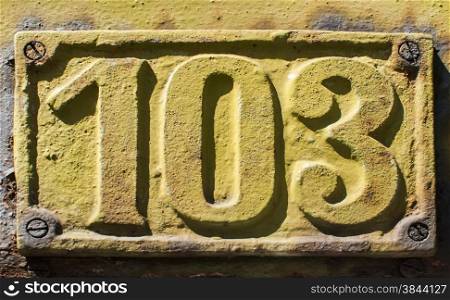 Old retro weathered painted cast iron plate with number 103