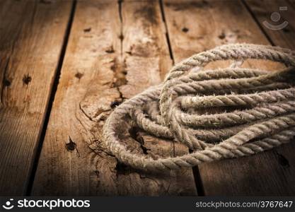Old rope twisted and tied in a bundle on a rough wooden background