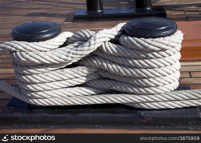 Old ropes around mooring bollard in a deck