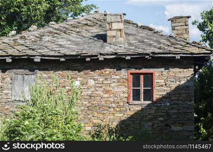 Old rural country house with roof stone slabs closeup
