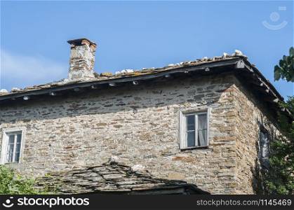 Old rural country stone house facade in sunny summer day