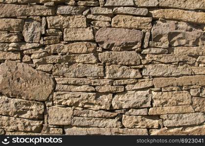 Old rural dry masonry stone wall closeup as background