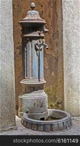 Old rusted public water tap in Italy
