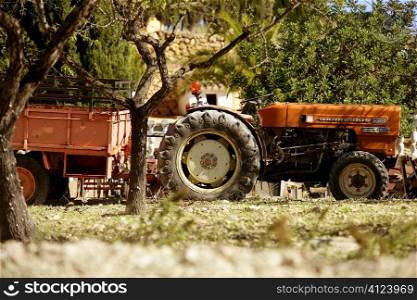Old rusted tractor orange color in Spain. Agriculture traditional vehicle