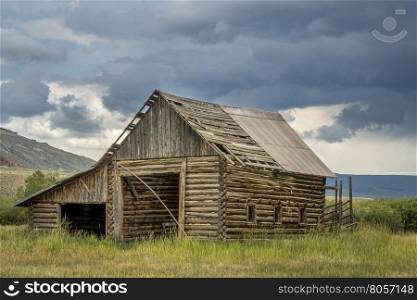 old, rustic, log barn in Colorado's Rocky Mountains with a stormy sky