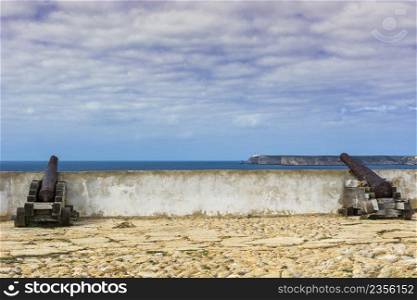 Old rusty cannon guarding the Portuguese fortress Sagres on the Atlantic Ocean beach. Breathtaking landscape and nature of the Portugal, popular travel destination in western Europe.
