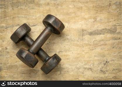 old rusty dumbbells on textured handmade bark paper with a copy space