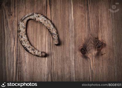 Old rusty horseshoe on vintage wooden board